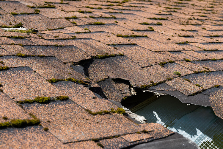 close-up of severely damaged shingle roofing